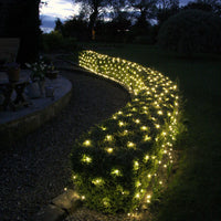 Core Connect Lichternetze mit warmweißen LEDs auf Gartenhecken entlang eines Weges