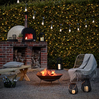 Essential Connect koppelbare Lichternetze mit warmweißen LEDs an einer Hecke im gemütlichen Gartenbereich