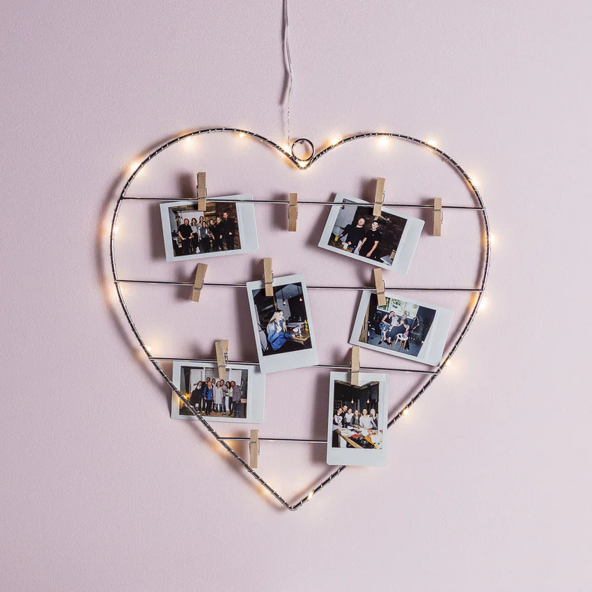 Beleuchteter herzförmiger Fotorahmen mit warmweißer Lichterkette und kleinen Holzklammern für Fotos