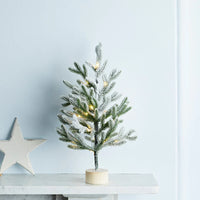 Kleiner warmweiß beleuchteter Weihnachtsbaum auf einem Kaminsims