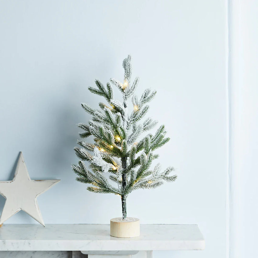 Kleiner warmweiß beleuchteter Weihnachtsbaum auf einem Kaminsims