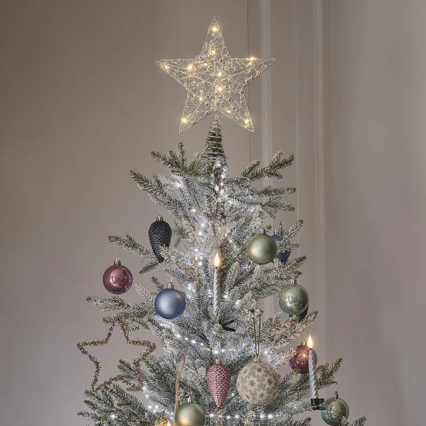 Warmweiße LED Weihnachtsbaumkerzen an den Zweigen eines Weihnachtsbaumes