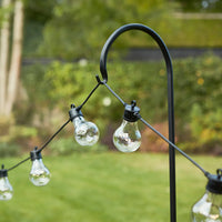 Lichterkette mit Glühbirnen an schwarzem Gartenhaken als Zubehör für Außenbeleuchtung