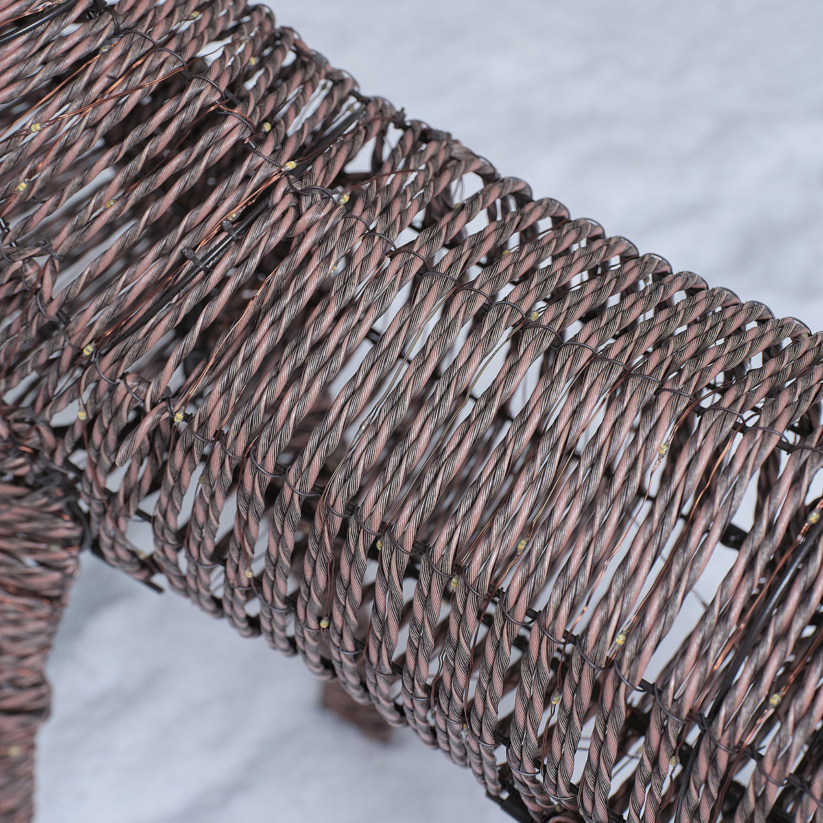 Nahaufnahme des Rattanrahmens mit Mikro-LEDs der LED-Rentierfigur im Schnee