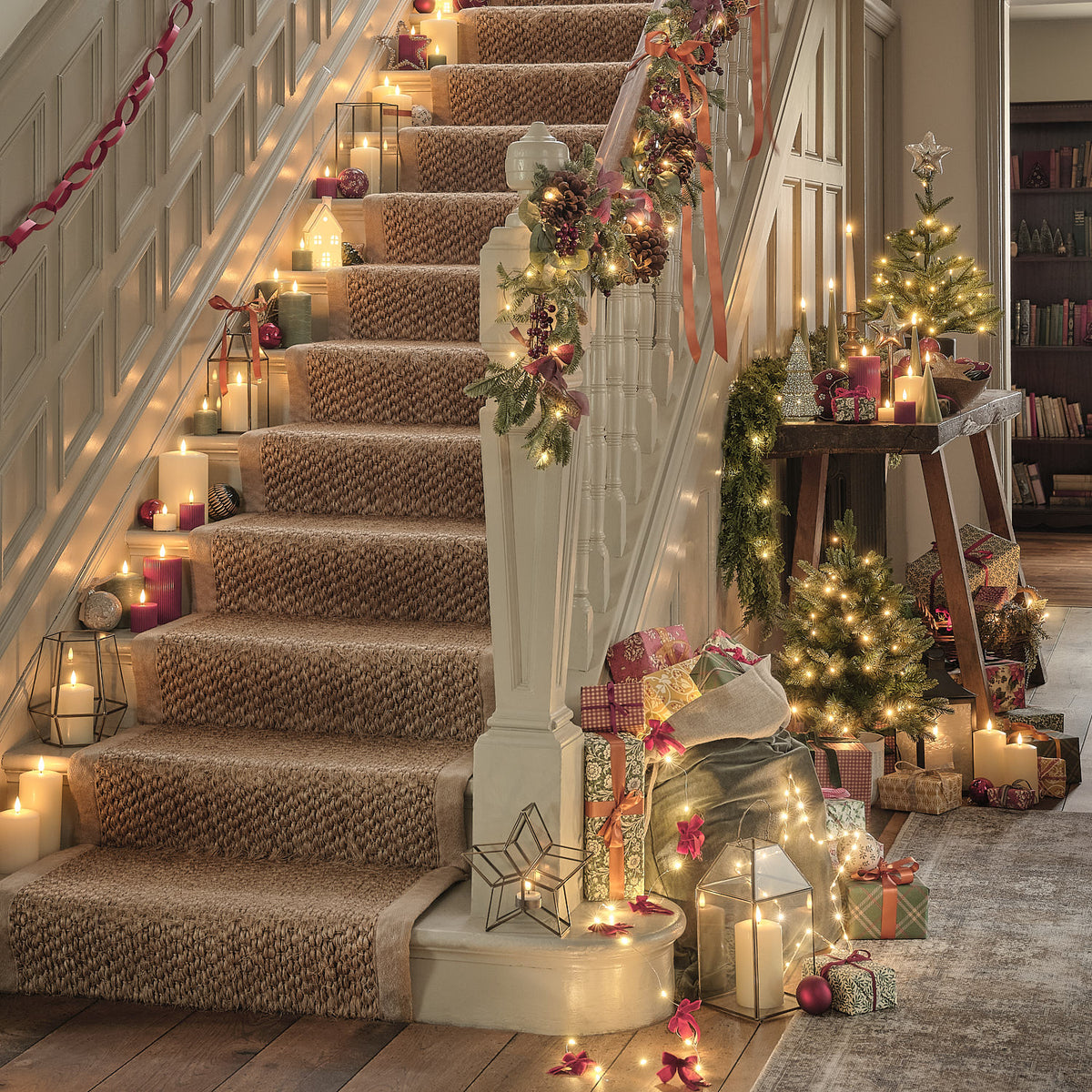 Weihnachtlich dekorierte Treppe mit Girlande, Kerzen und Geschenken im warmen Licht