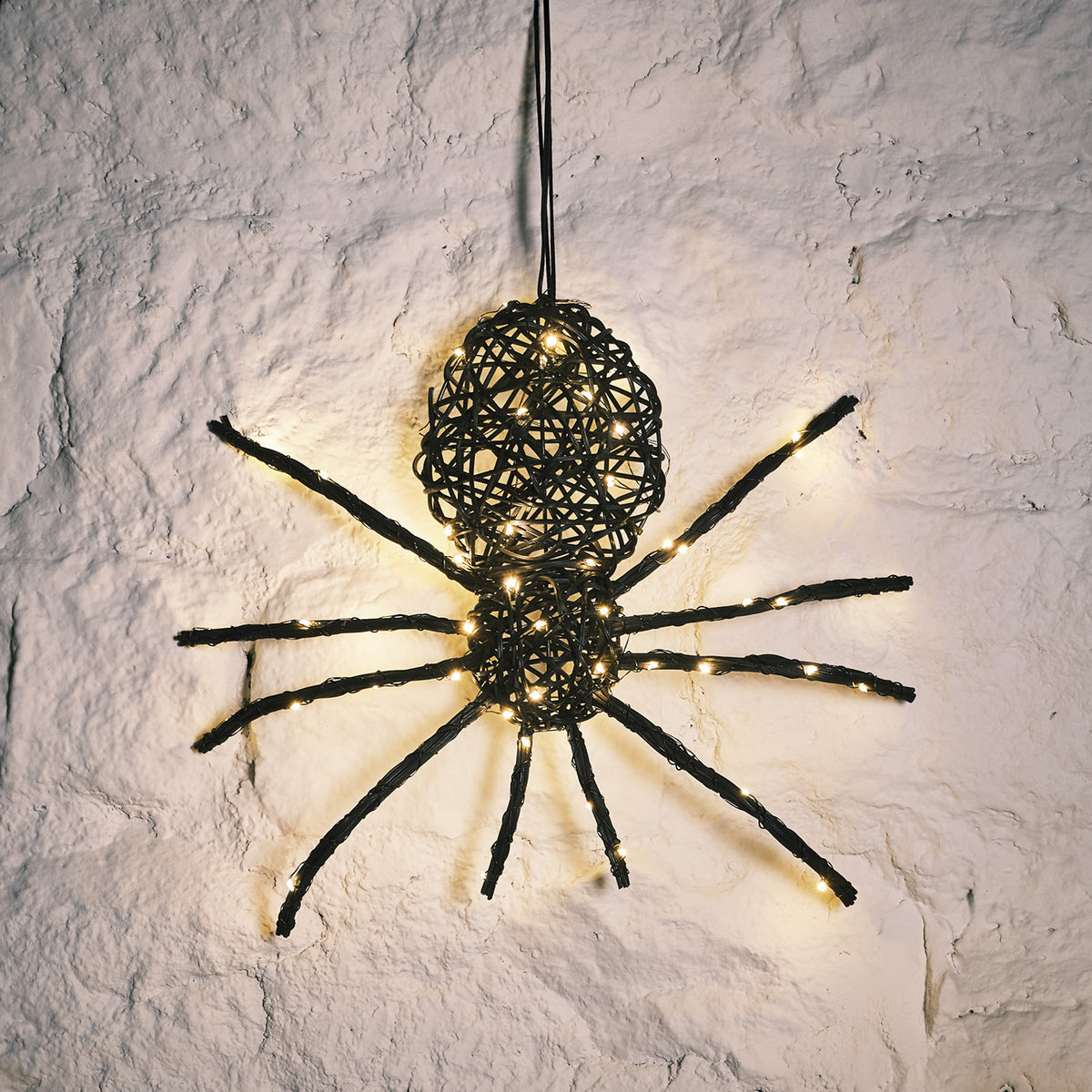 LED beleuchtete Rattan-Spinne mit warmweißen Lichtern an weißer Wand