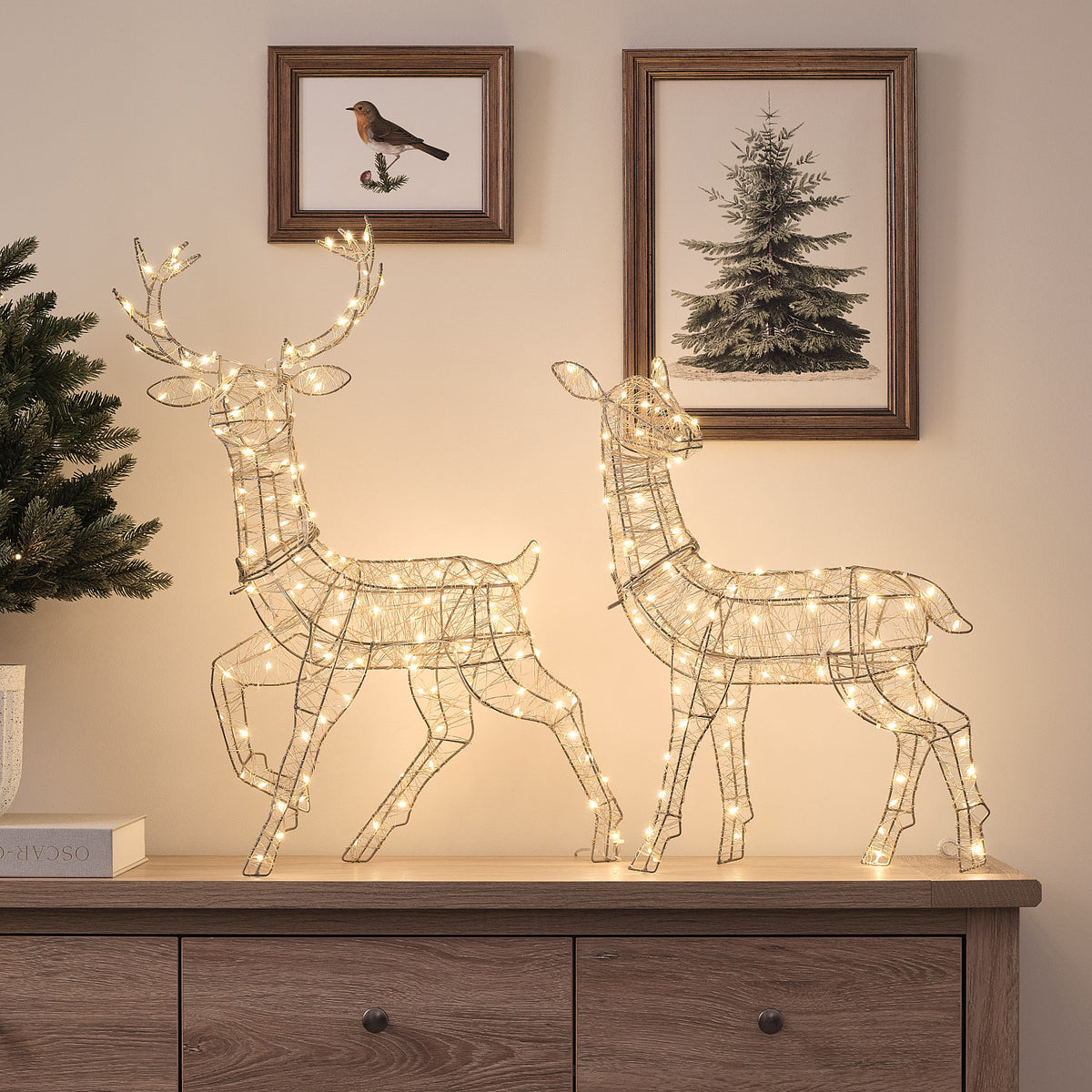 Goldene LED-Rentiere Hirsch und Hirschkuh leuchtend auf Sideboard vor Wand mit Bildern