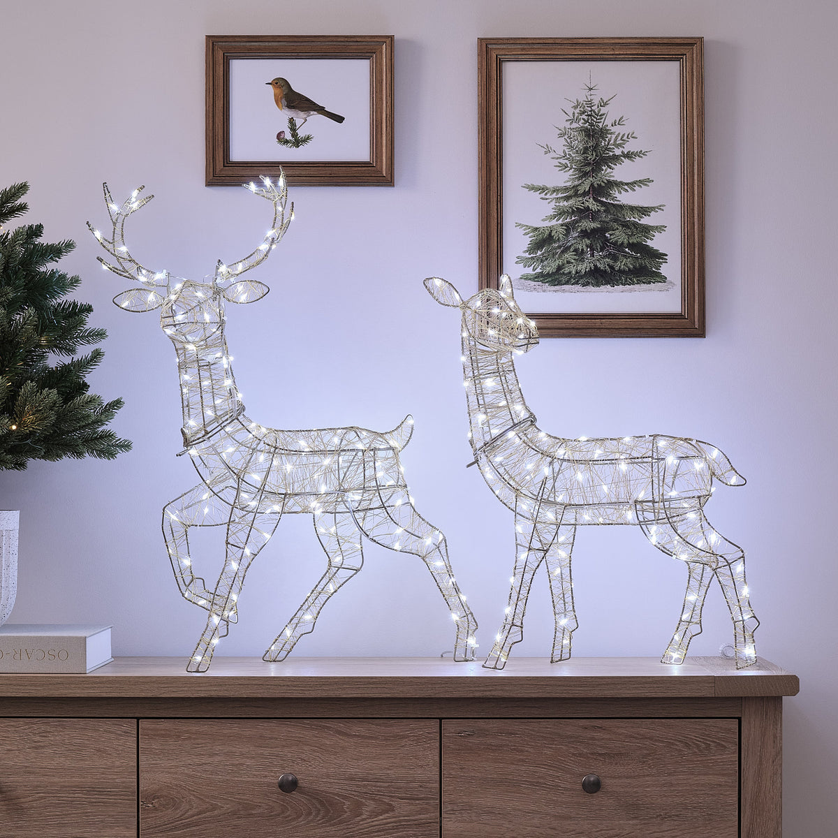 LED-Rentiere Hirsch und Hirschkuh mit kaltem Weißlicht auf Sideboard vor Wand mit Bildern