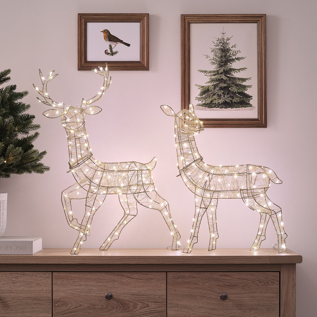 Goldene LED-Rentiere Hirsch und Hirschkuh mit warmweißem Licht auf Sideboard vor Wand