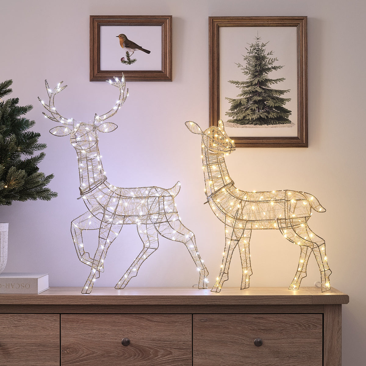 Goldenes LED-Rentier Hirschkuh neben beleuchtetem LED-Rentier Hirsch mit Geweih auf Holzkommode