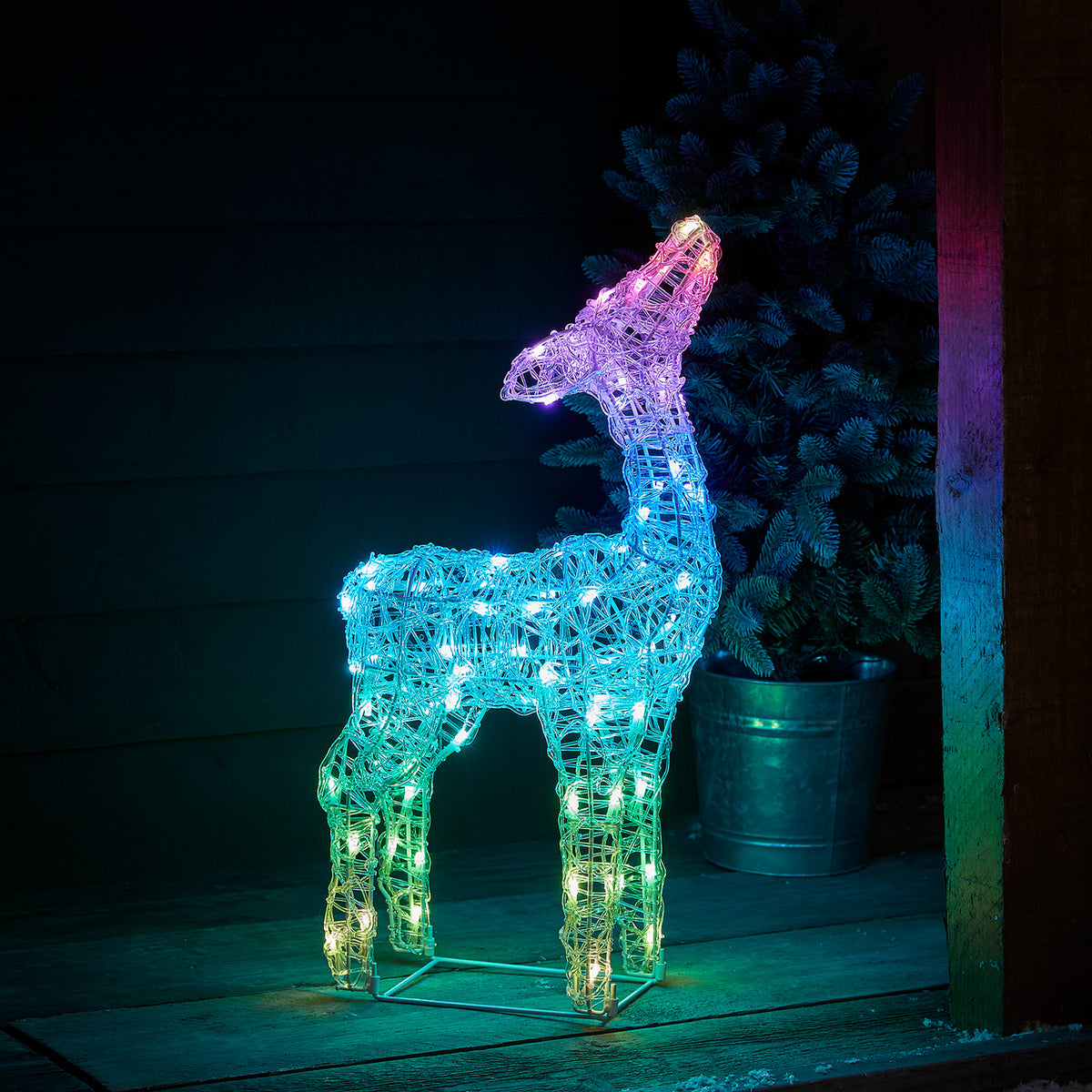 LED-Rehkitz pink leuchtend vor dunkler Holzfassade auf Holzterrasse