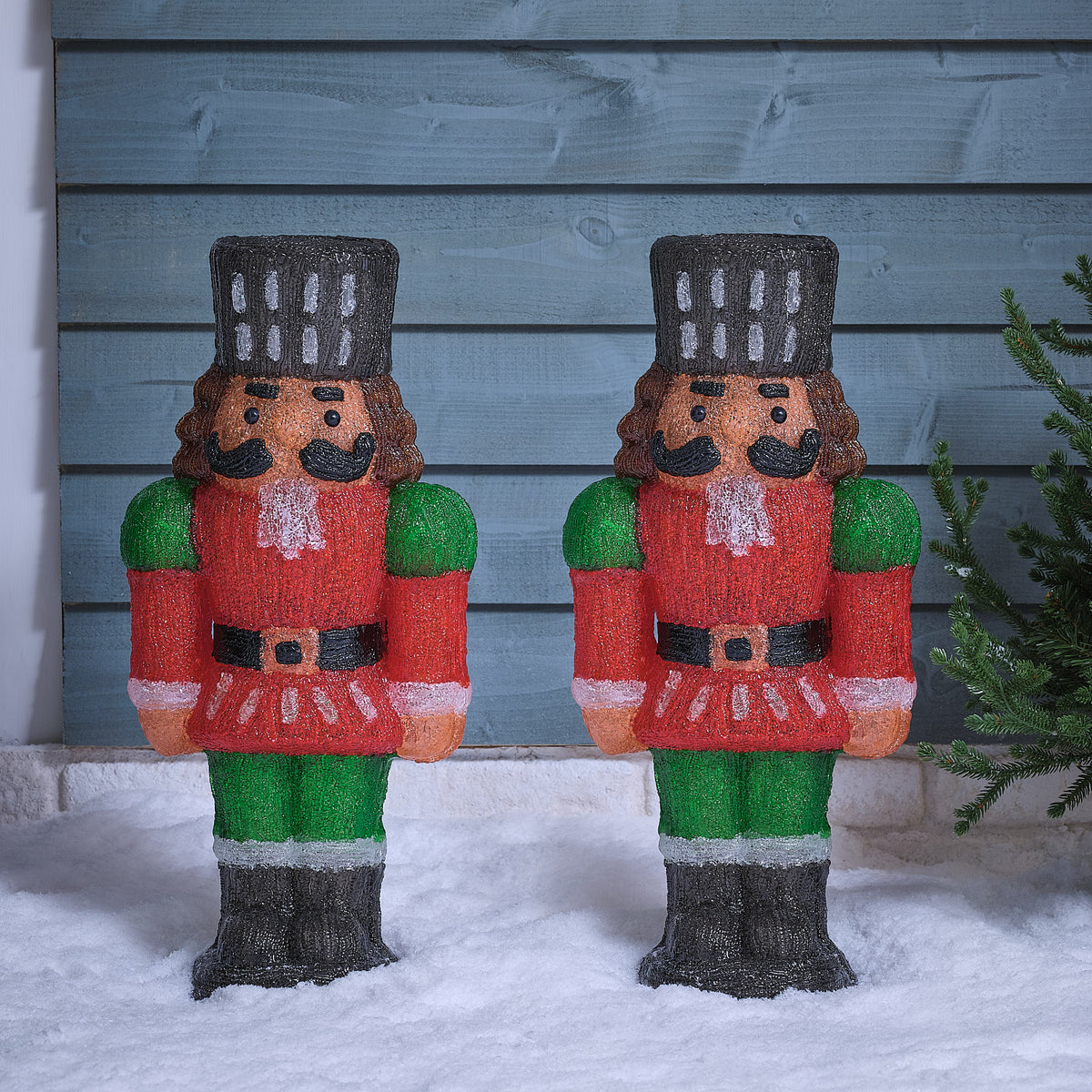 Zwei unbeleuchtete LED-Nussknacker aus Acryl mit roter Uniform und schwarzem Hut im Schnee