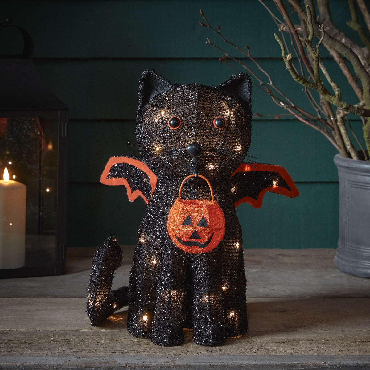 Nahaufnahme der beleuchteten Fledermaus-Katzenfigur mit Kürbis-Körbchen in Halloween-Deko