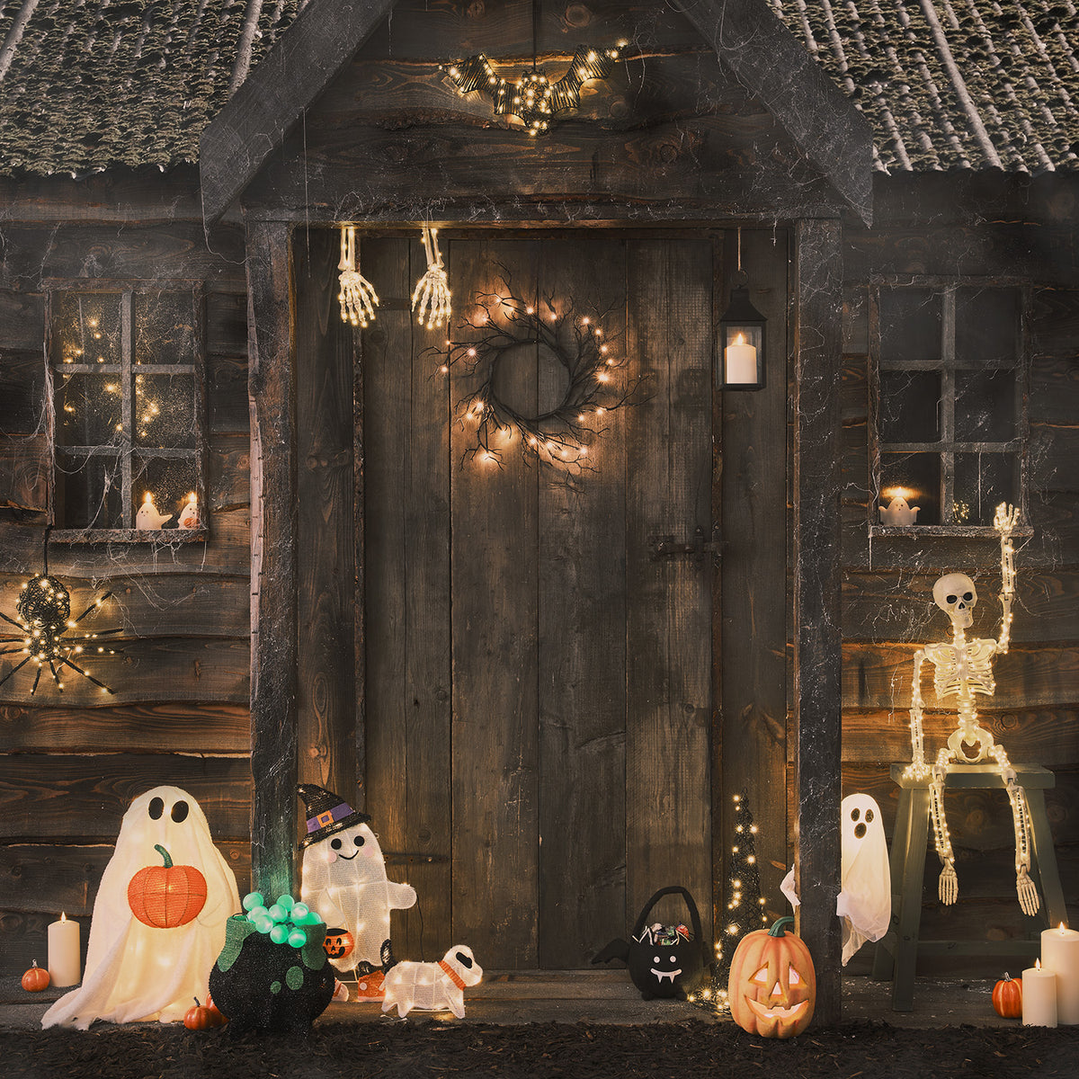 Halloween-Dekoration mit leuchtendem Geist, Hund, Kürbis und Skelett vor Holztür