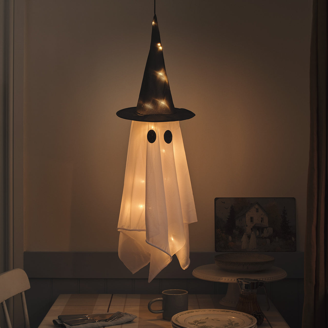 Hängender LED-Geist Winnie mit Hexenhut am Abend beleuchtet