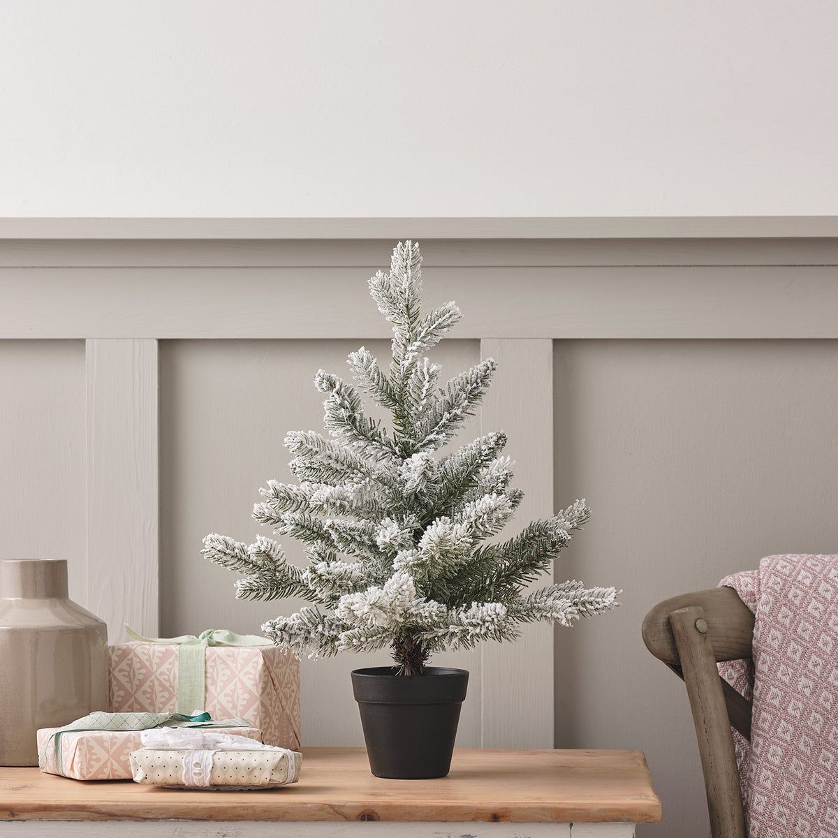 45cm kleiner künstlicher Weihnachtsbaum mit Schneeeffekt in schwarzem Topf auf Holztisch neben Geschenken