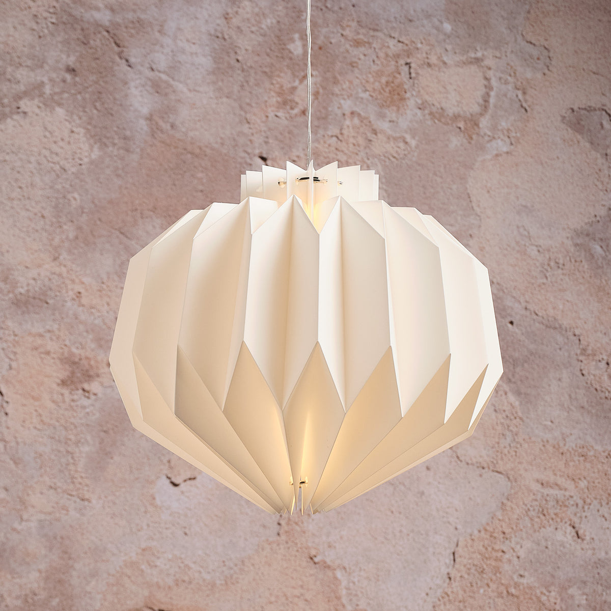 Nahaufnahme der beleuchteten Shrewsbury LED-Papier-Pendelleuchte mit warmweißem Licht vor Wand