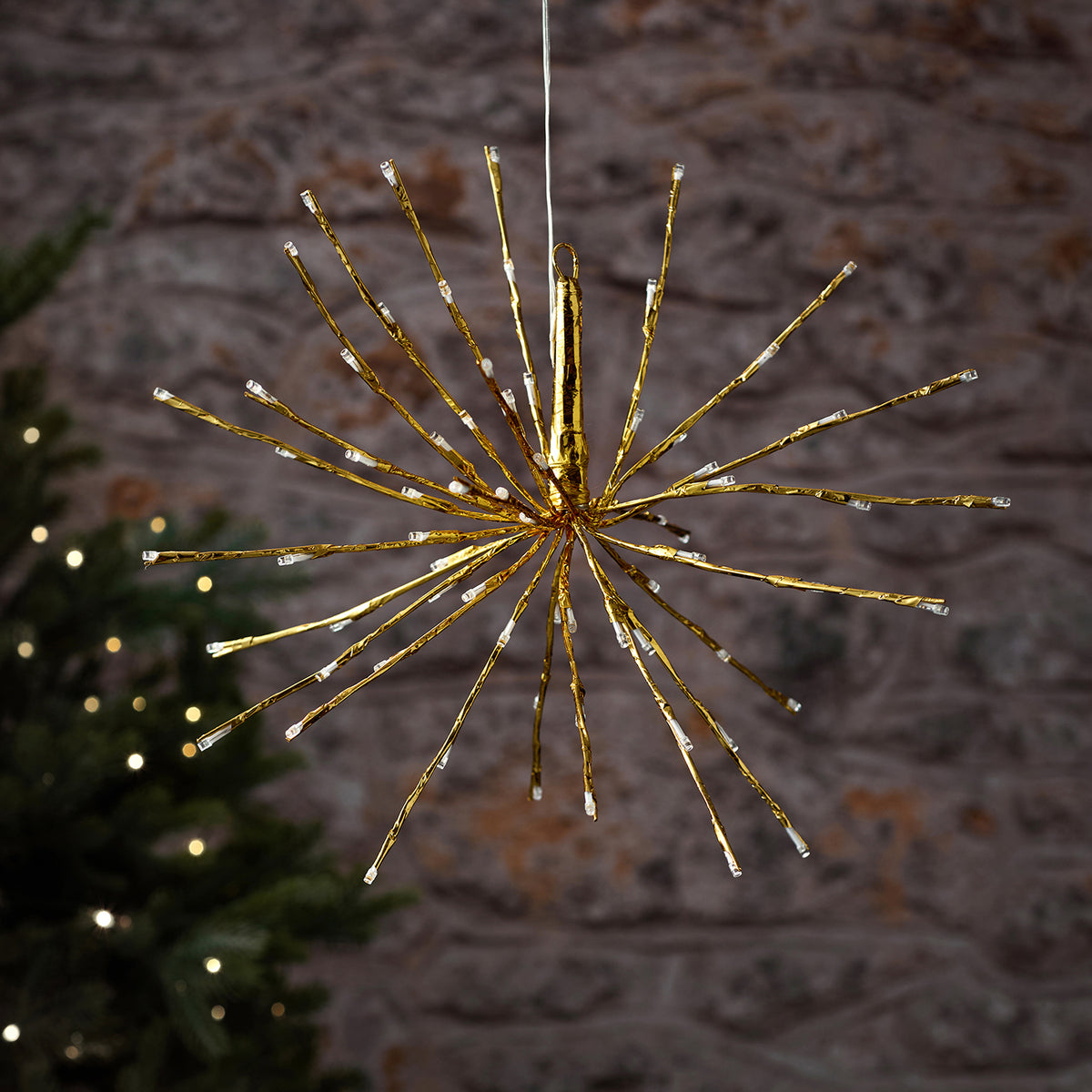 Elegante hängende LED-Stern-Dekofigur mit warmweißer strahlenförmiger Beleuchtung und grünem Grünflächen-Hintergrund, arrangiert als Außendekoration – festliche Hänge-Lichterkette mit atmosphärischer Weihnachtsstimmung für Fassaden und gehobene Außendekoration.