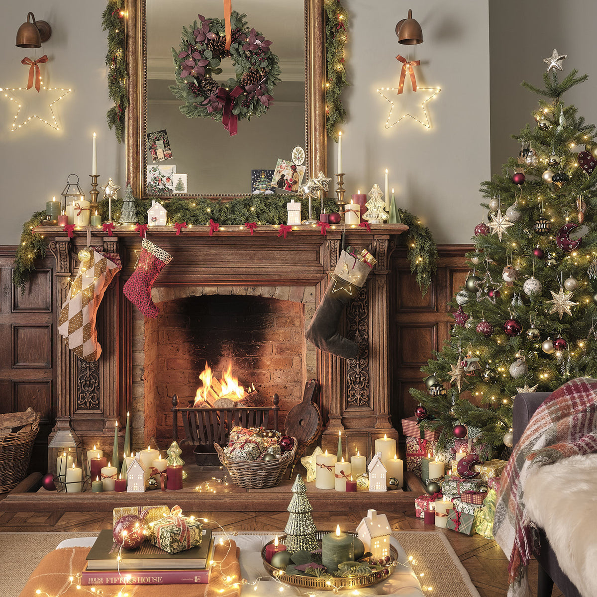 Weihnachtlich dekoriertes Wohnzimmer mit Kamin, Laterne und geschmücktem Baum.