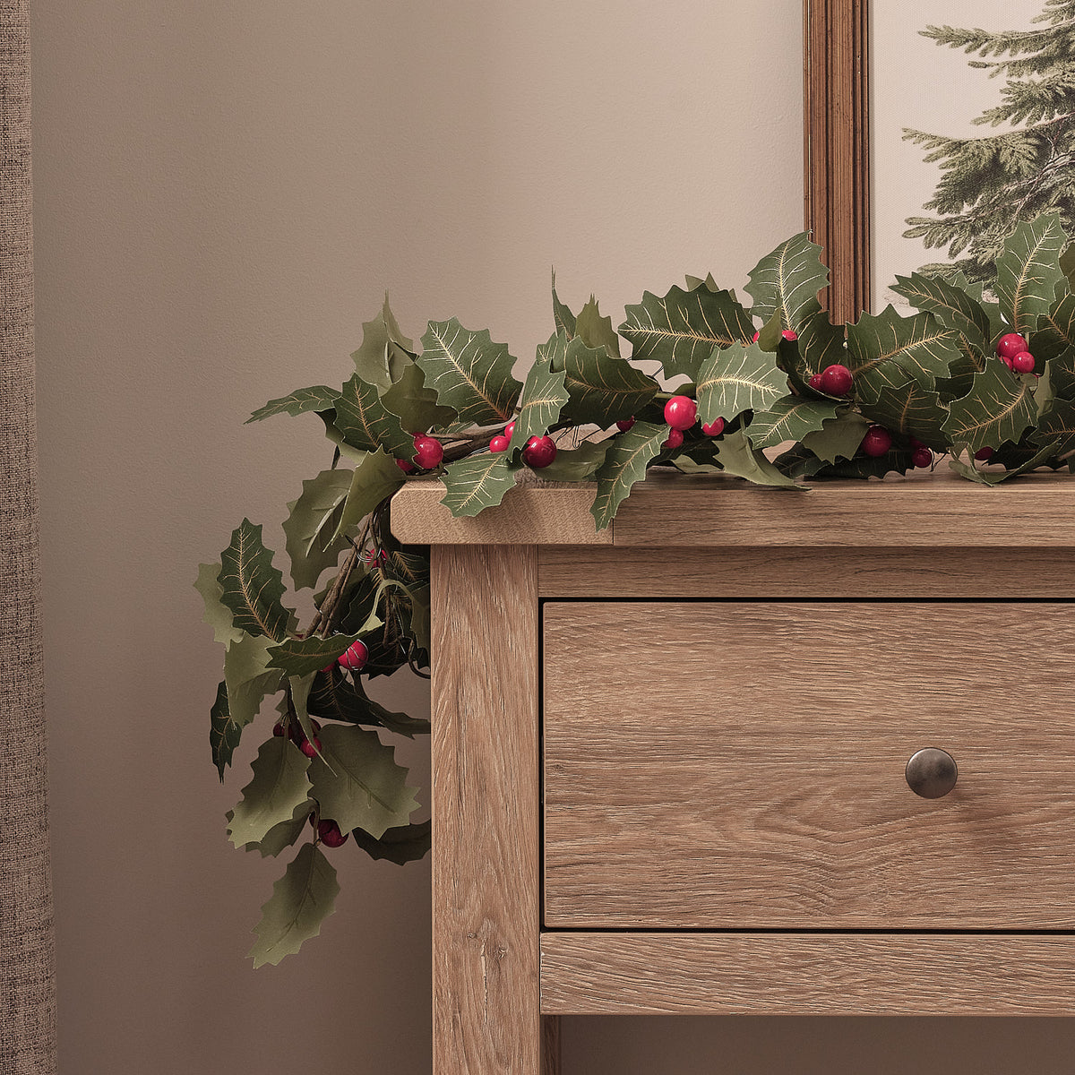 Stechpalmen-Girlande mit warmweißen LEDs dekorativ auf einer Holzkommode platziert