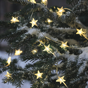 LED Stern Lichterkette mit warmweißen Sternen an einem schneebedeckten Tannenzweig