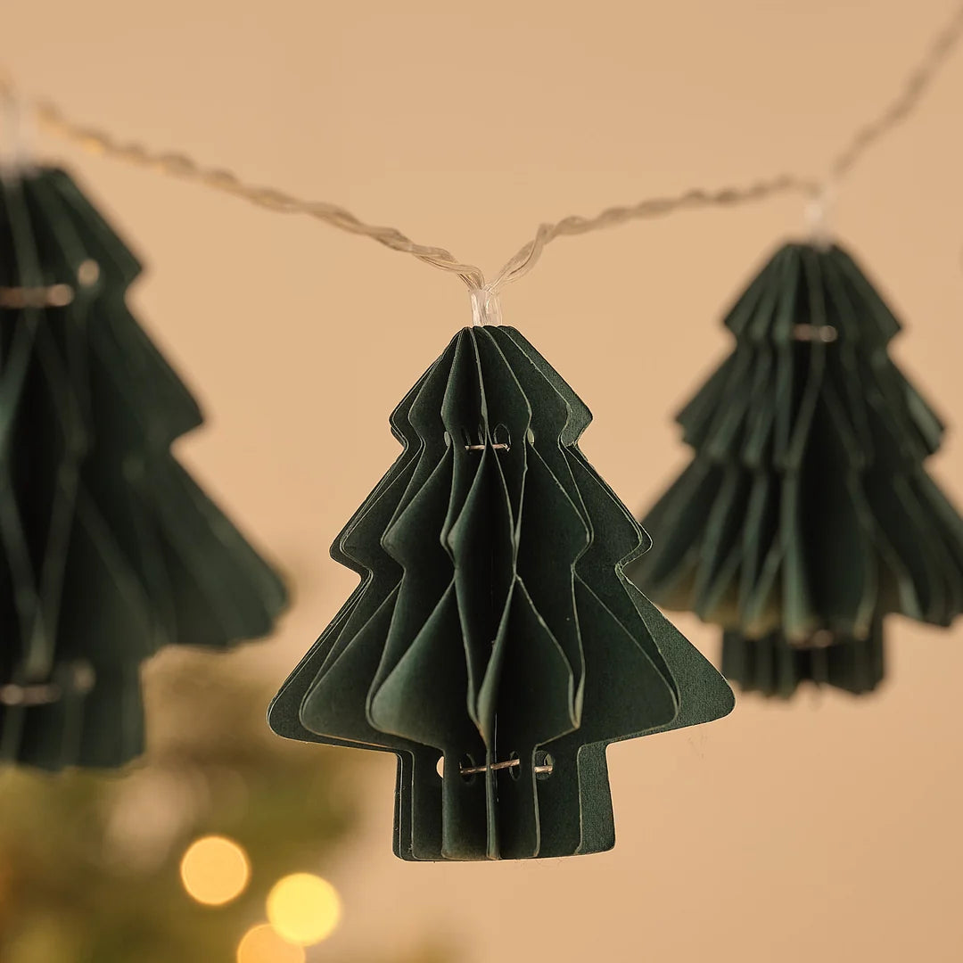 Grüner Papier-Tannenbaum-Anhänger an Lichterkette, Nahaufnahme.