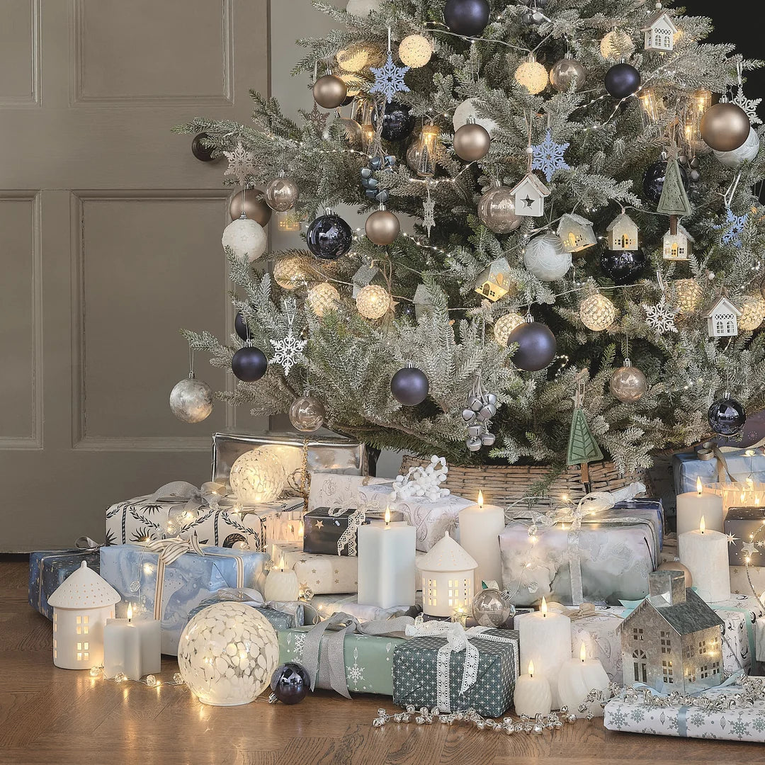Weiß-blau geschmückter Weihnachtsbaum mit Geschenken im Wohnzimmer.