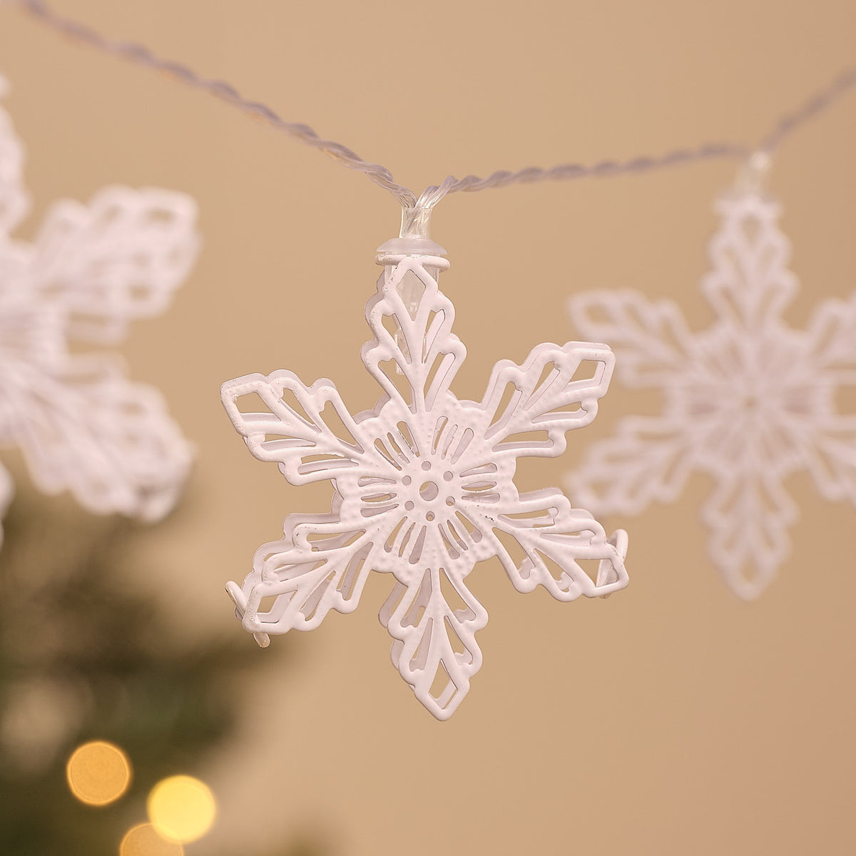 Detailansicht einer weißen Metall-Schneeflocke mit warmweißem LED-Licht an Lichterkette