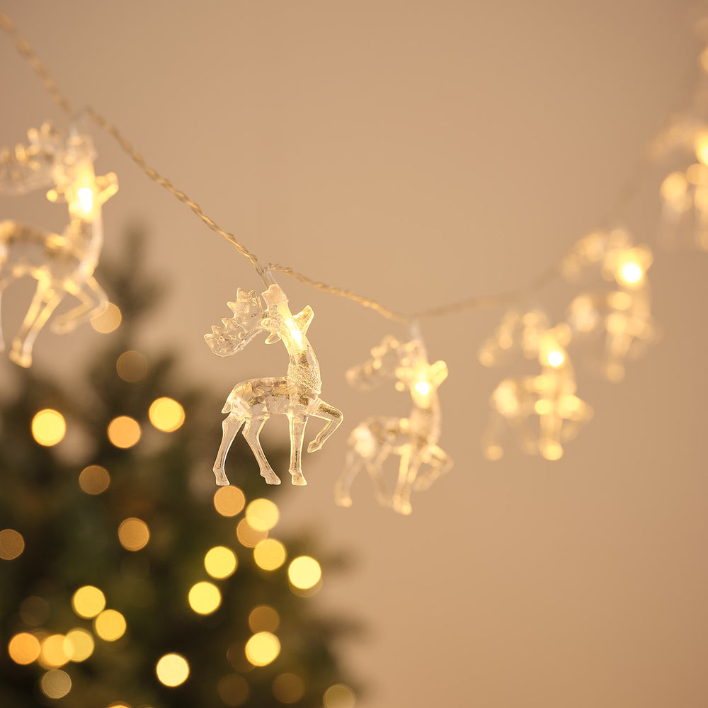 Batteriebetriebene Rentier-Lichterkette mit 20 warmweißen LEDs vor unscharfem Weihnachtsbaum