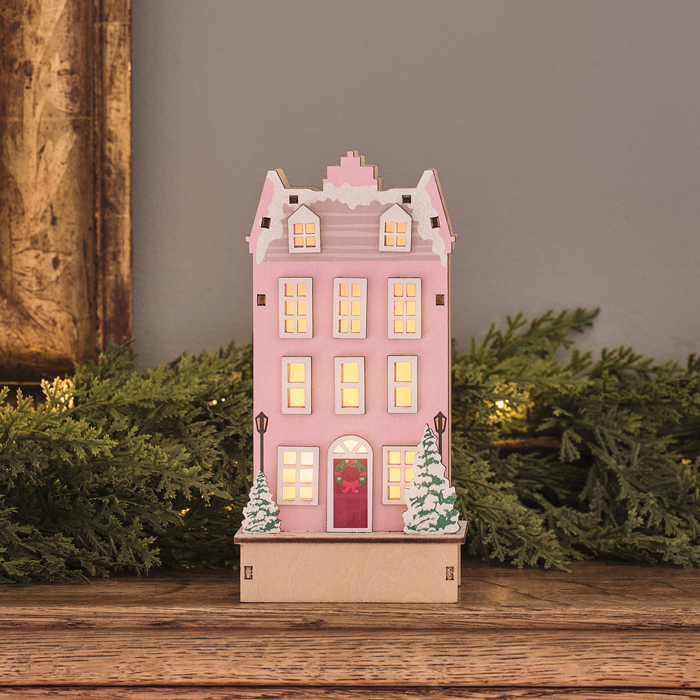 Beleuchtetes LED-Holzhaus in Rosa mit warmweiß leuchtenden Fenstern und winterlicher Dekoration