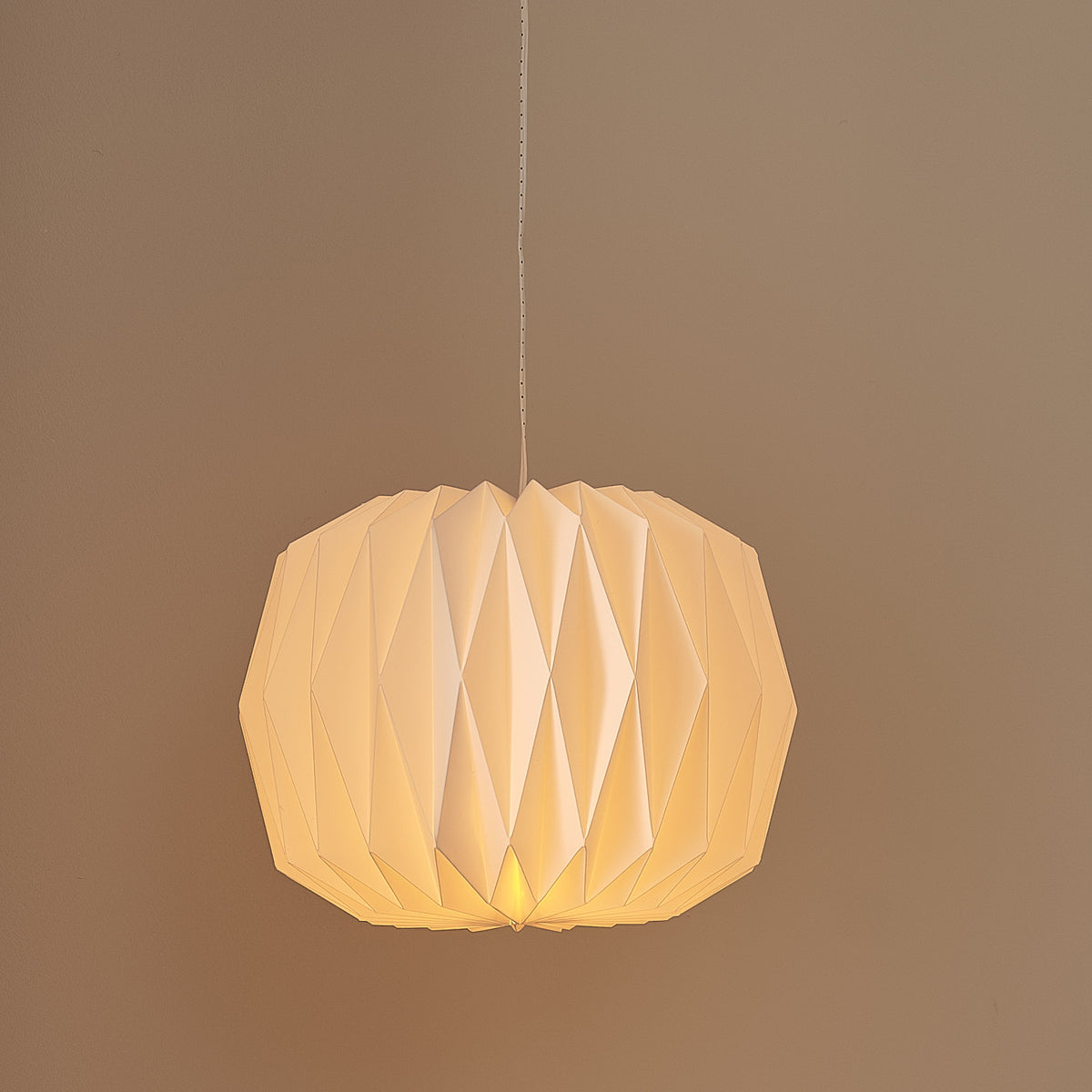 Weiße LED-Papierlaterne mit warmweißem Licht an grauer Wand mit Weihnachtsdeko