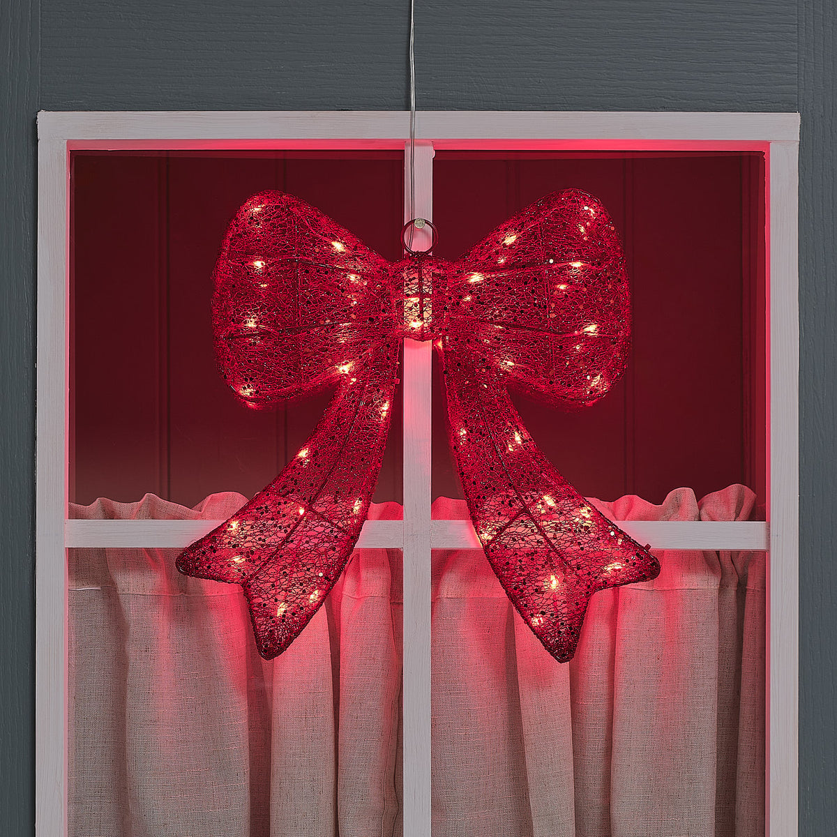Rote LED-Weihnachtsschleife mit 35 Mikro-LEDs leuchtet an einem Fenster bei Dunkelheit