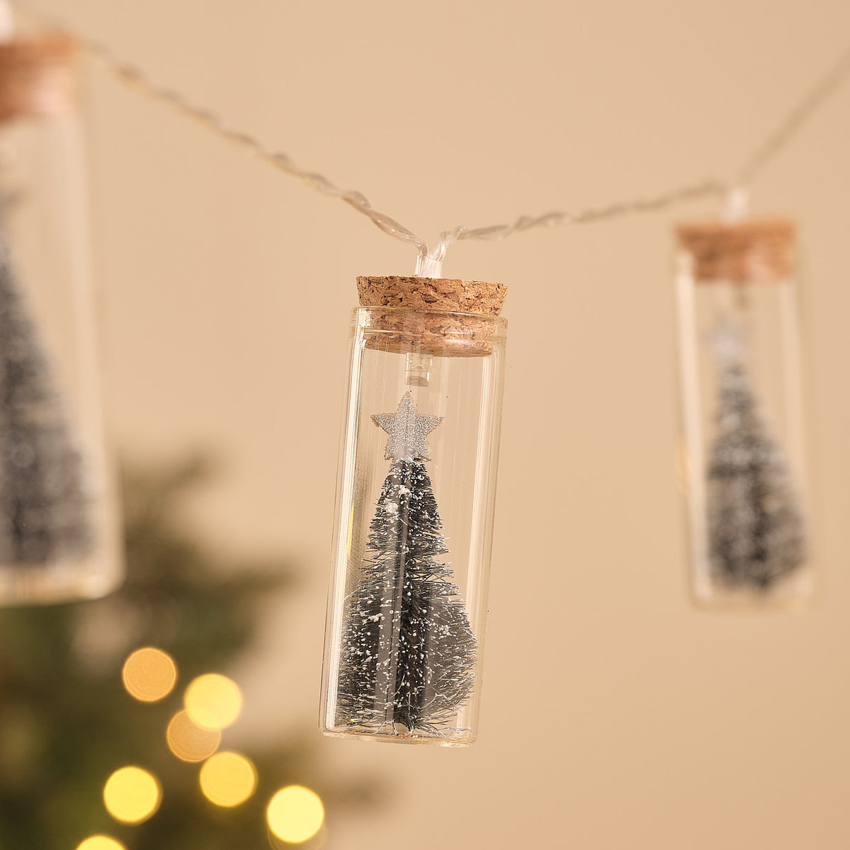 Beleuchtete Glasflasche mit Mini-Tannenbaum und goldenem Stern, Teil einer LED-Lichterkette