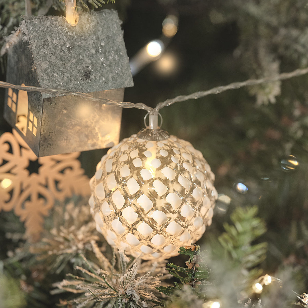 Gefrostete LED-Glaskugel der Lichterkette an einem Weihnachtsbaum mit Dekoration