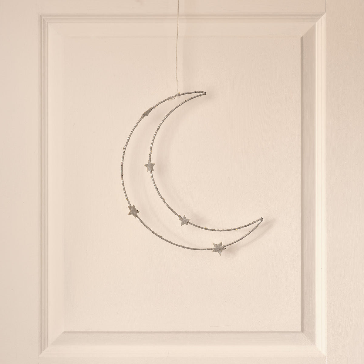 Silberner LED-Mond mit Sternen an weißer Wand, warmweiße LEDs leuchten