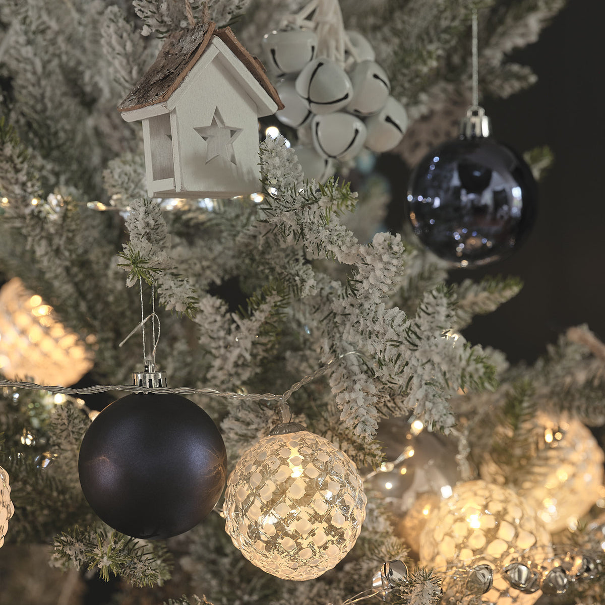 Weihnachtsbaum mit gefrosteten LED-Glaskugeln, schwarzen Kugeln und Holzdeko