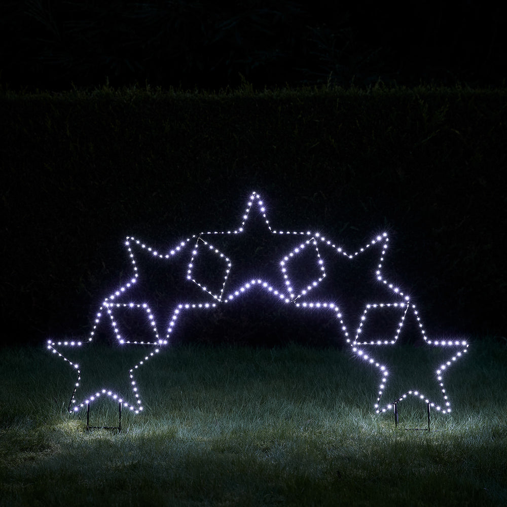 Fünf Sterne als Lichterbogen mit weißen LEDs im Garten bei Nacht
