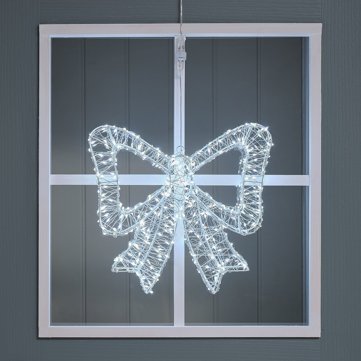 Bicolor LED-Schleife außen in Weiß leuchtend an einem Fensterrahmen