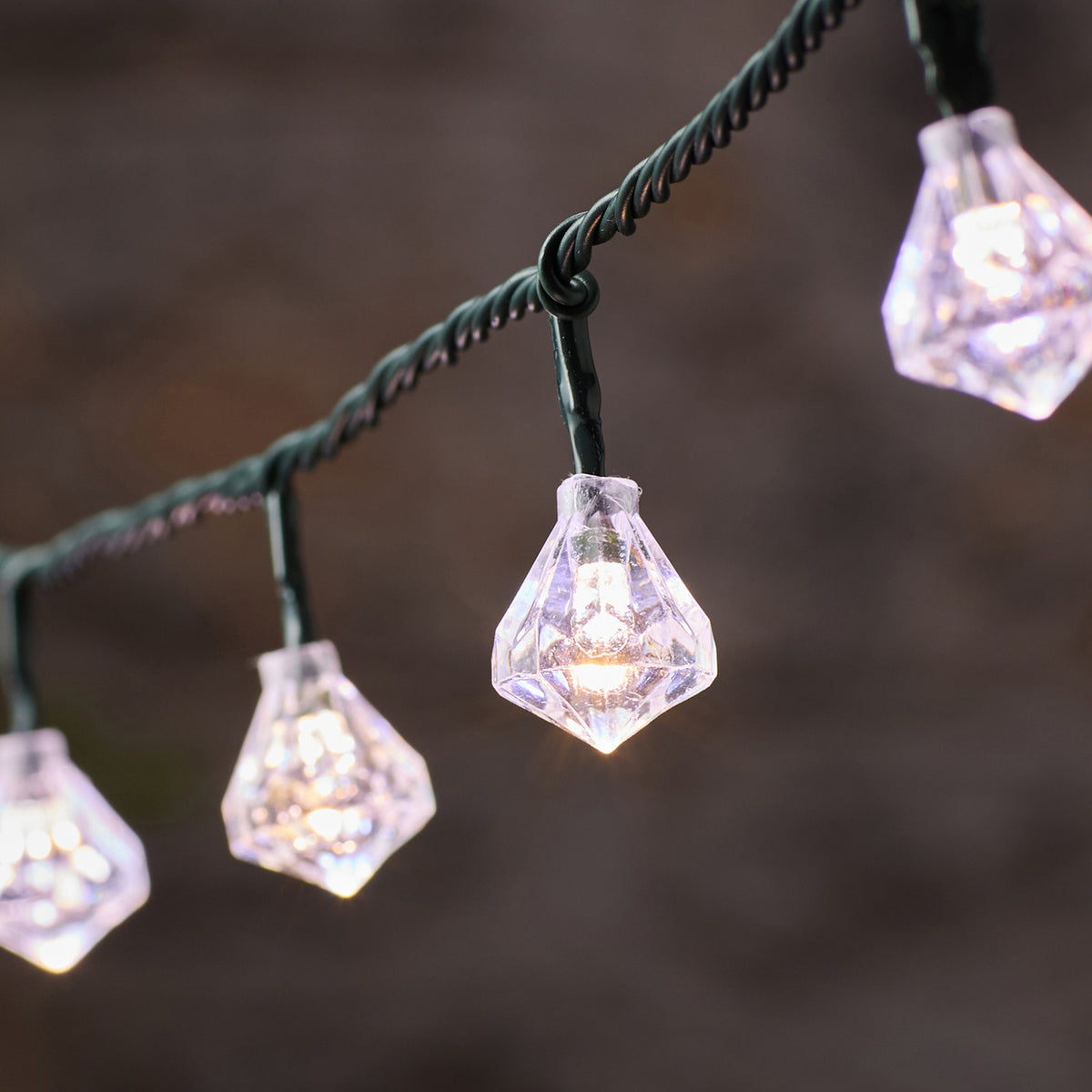 Nahaufnahme einer weißen LED mit facettierter Diamantkappe an grünem Kabel