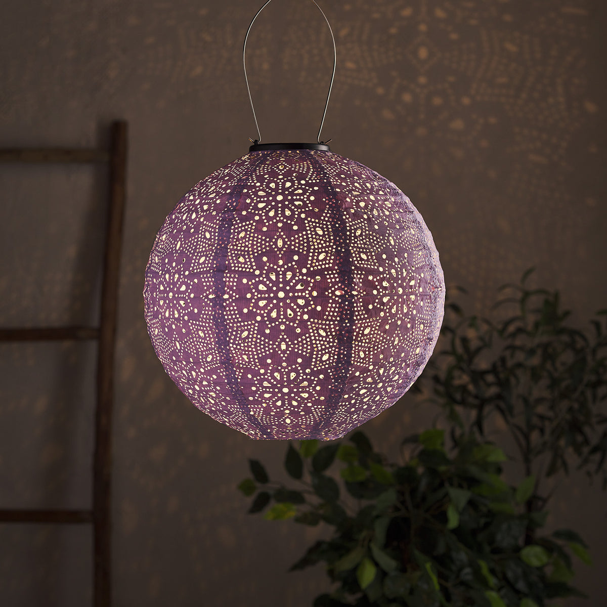 Leuchtender lila runder Tyvek Solar-Lampion mit Blumenmuster vor dunklem Hintergrund