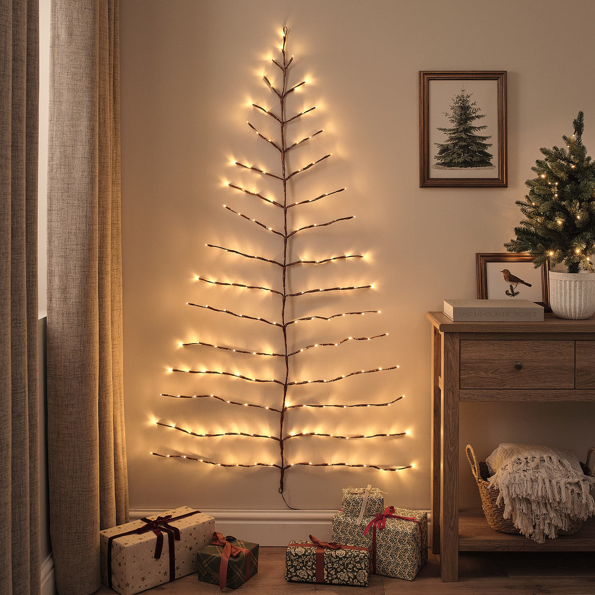 LED-Wandbaum mit warmweißen Lichtern an einer Wohnzimmerwand neben Kommode und Weihnachtsdeko