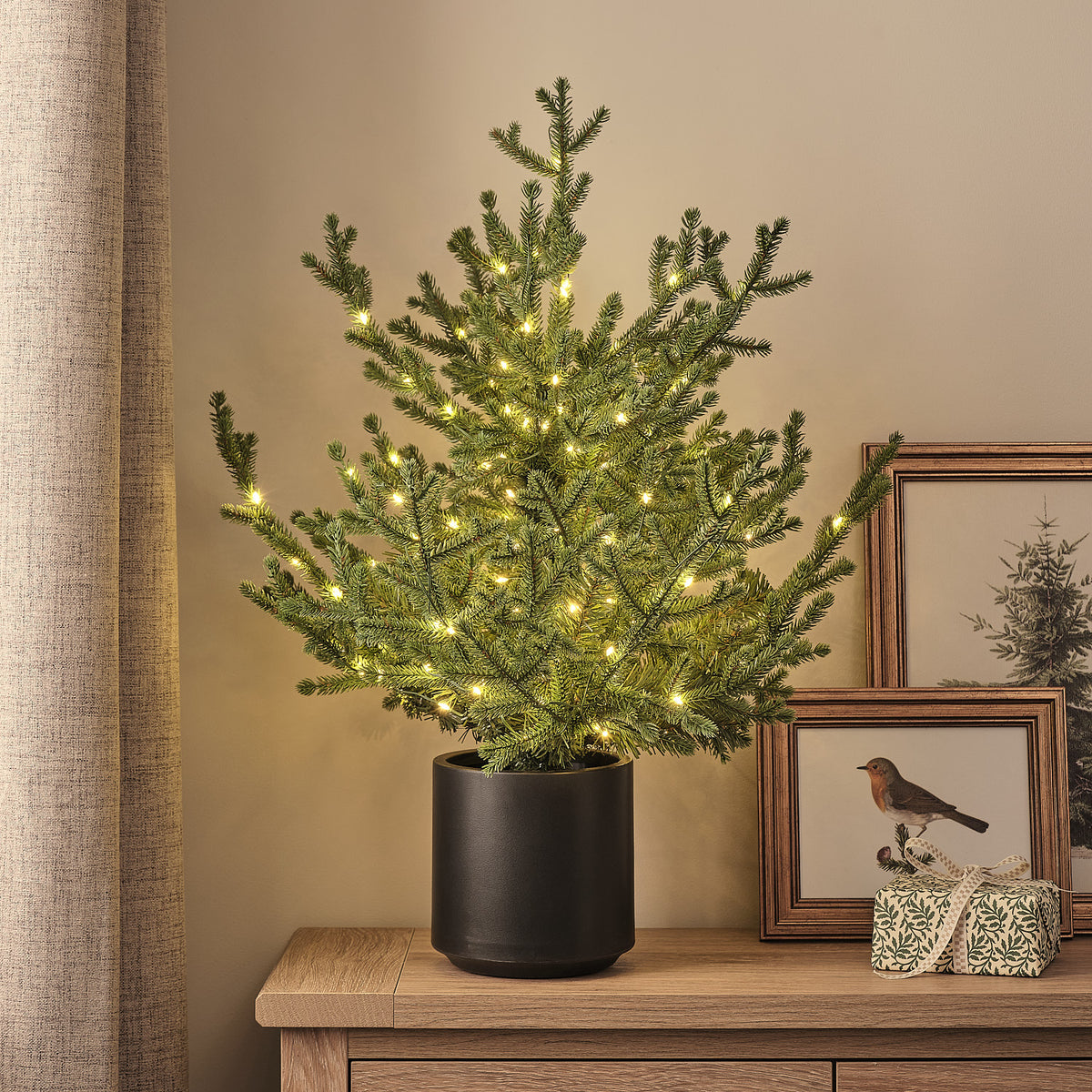 60 cm hoher LED-Weihnachtsbaum im schwarzen Topf mit warmweißen Lichtern auf Holztisch