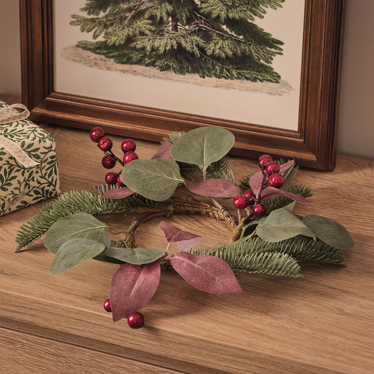 25cm Kerzenring mit roten Beeren und dunkelgrünem Kunstlaub auf Holztisch vor Weihnachtsbild