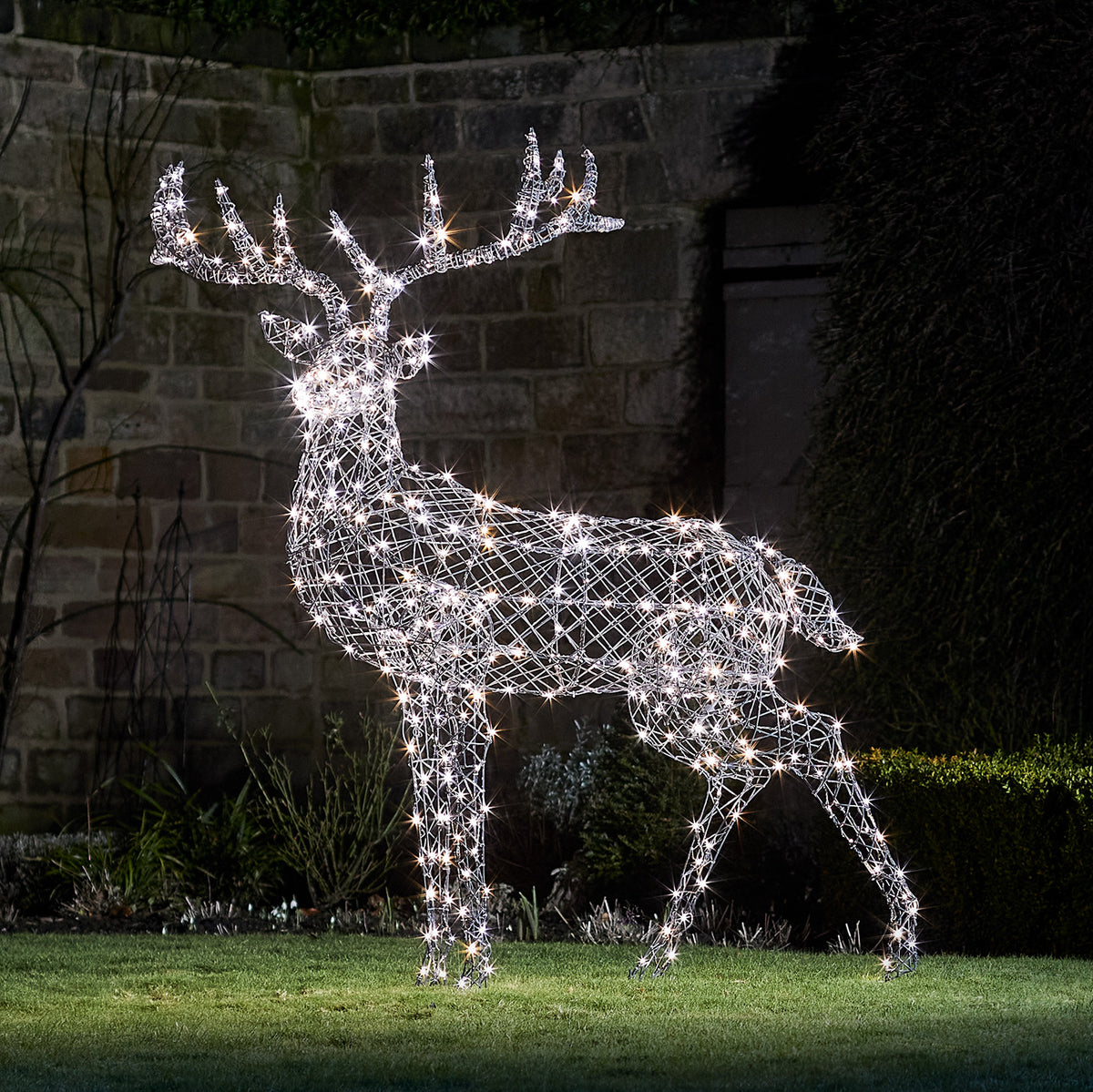 Solar-LED-Rentier in grauer Rattan-Optik mit warmweiß leuchtenden LEDs im Garten bei Nacht