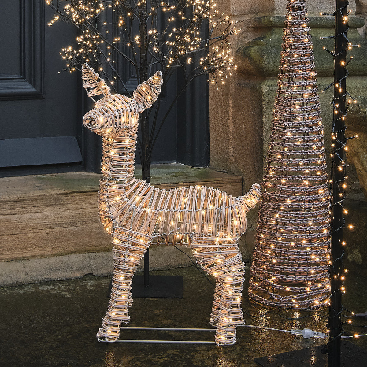 62 cm Leyburn Bicolor LED-Rehkitz aus Rattan mit 110 Mikro-LEDs in Warmweiß vor einem winterlichen Haus