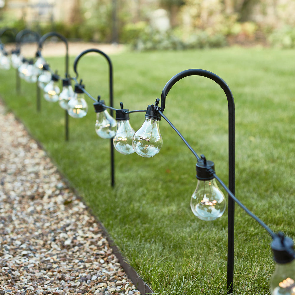 Party Lichterkette im Garten an schwarzen Schäferhaken als Wegbeleuchtung.