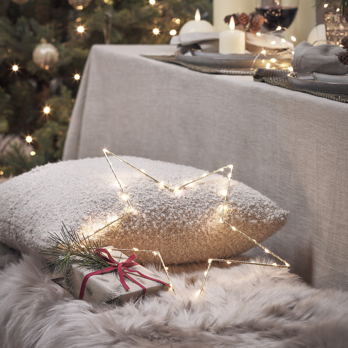 Weihnachtlich dekorierter Raum mit Kaminofen, Sessel, Geschenken und LED-Stern