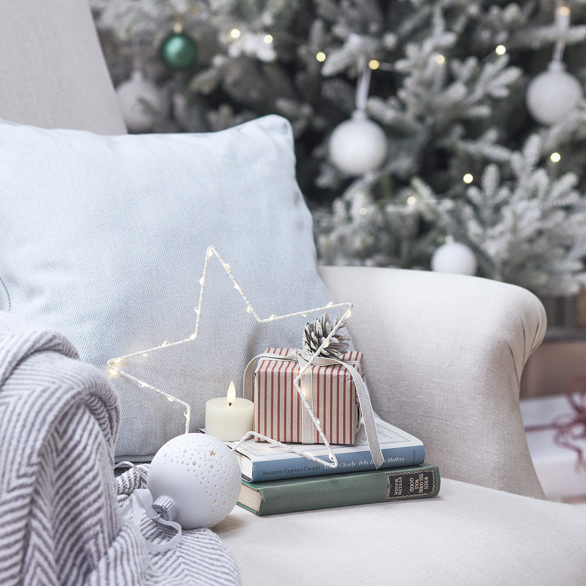 LED-Stern auf Couchkissen mit Geschenk und weichem Fell vor Weihnachtsbaum