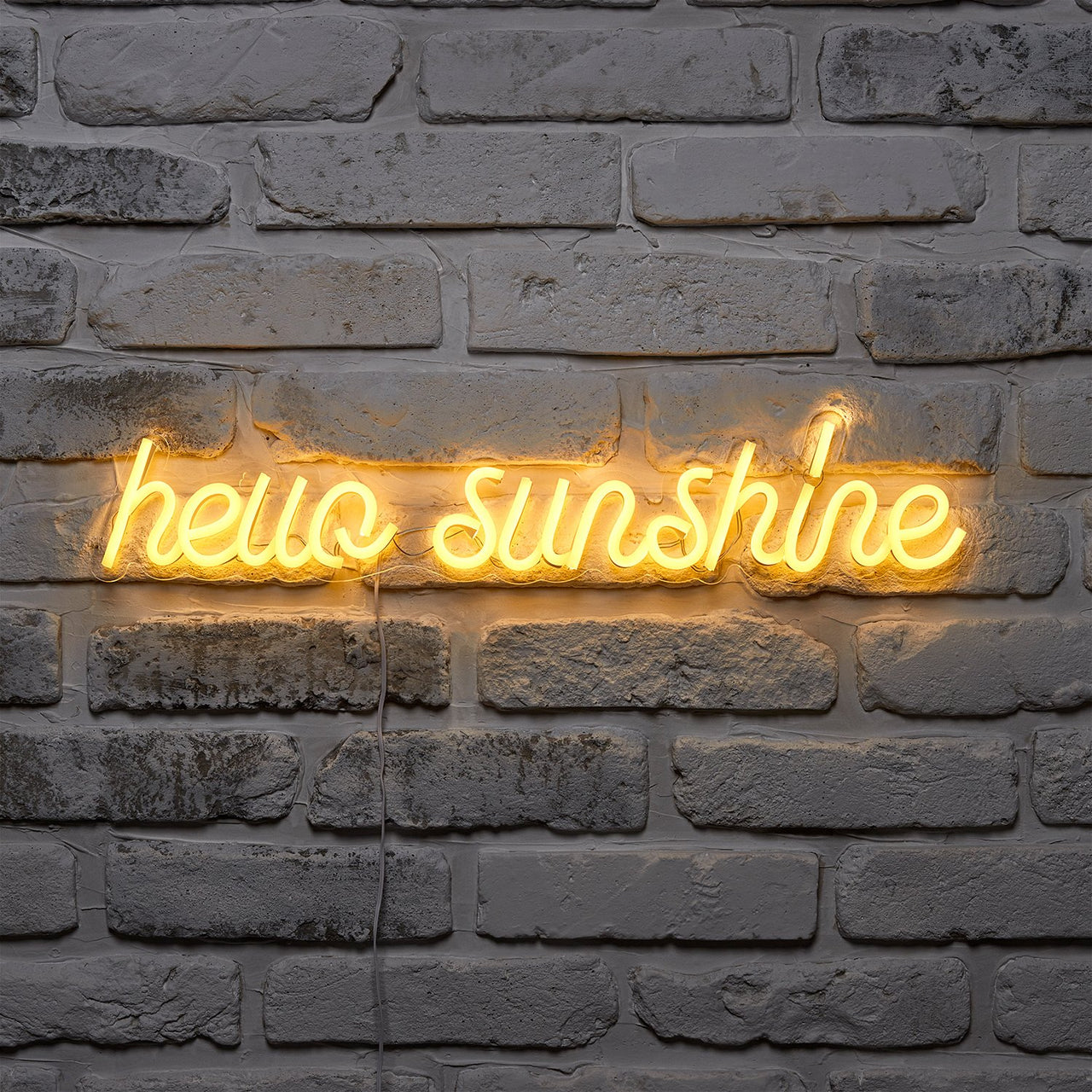 Dunkle Ziegelwand mit Neonschrift hello sunshine in Gelb.