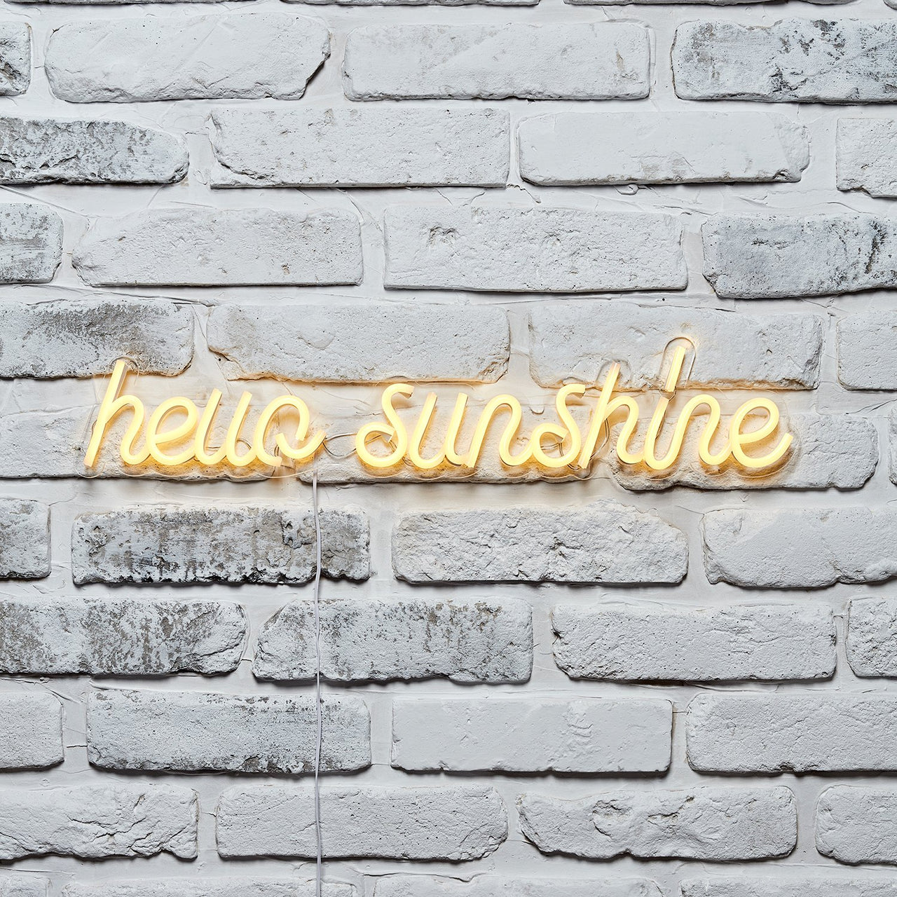 hello sunshine gelbe Neonschrift an weißer Ziegelwand.